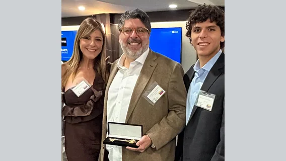Three people with name tags smiling, the man in the middle holding an open case with a gold key